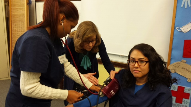 Sandy teaches a student how to take a blood pressure.
