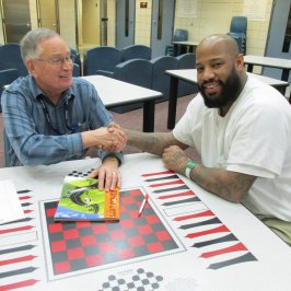 About_Impact-Header IVC Volunteer playing board games with a member of an elderly center